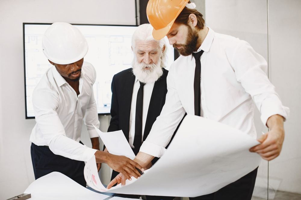 Trois architectes examinant des plans de bâtiment en bureau