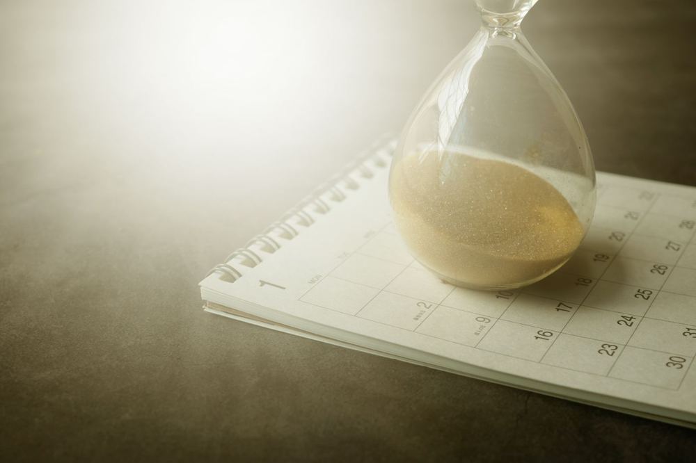 Sablier posé sur un calendrier, symbole du délai d’instruction