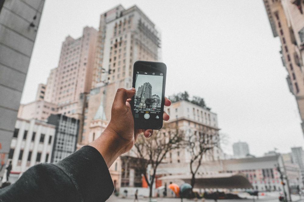 Personne photographiant la façade d’un bâtiment moderne avec un téléphone