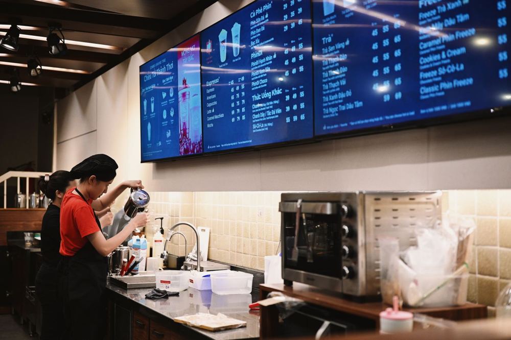 Baristas préparant des boissons dans un café avec écrans de menu digital