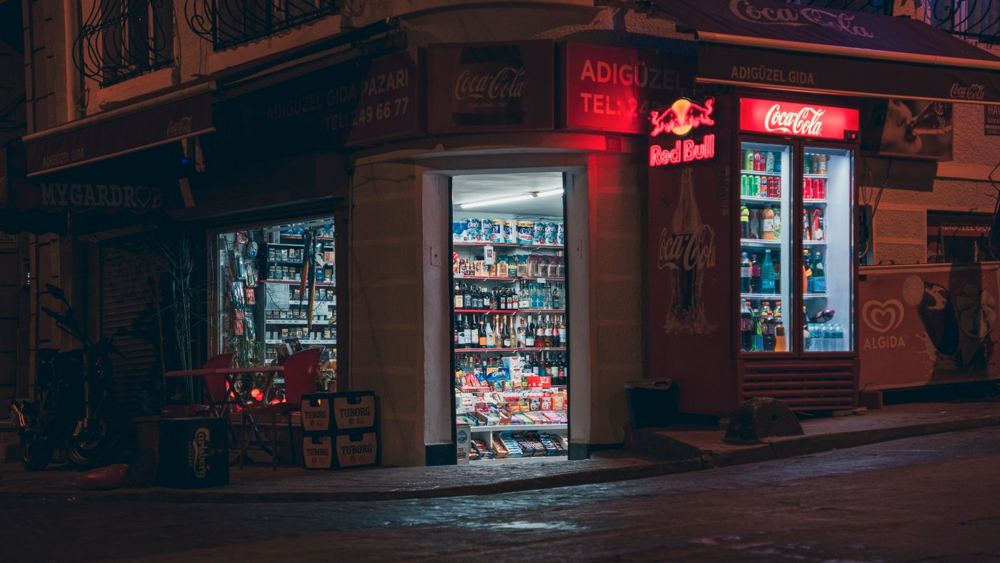 Commerce d’angle de rue avec enseigne lumineuse visible des deux côtés