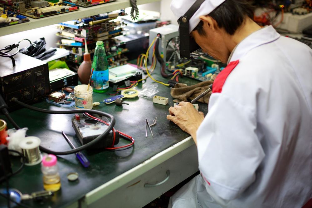 Technicien réparant un composant électronique sur établi