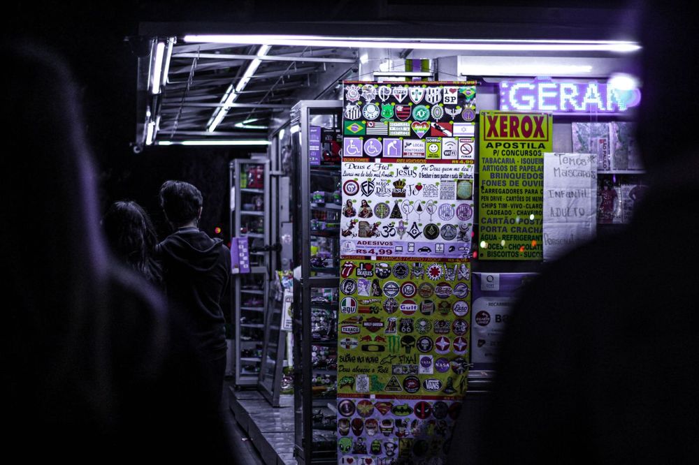 Façade de commerce avec enseigne allumée de nuit, rue commerçante