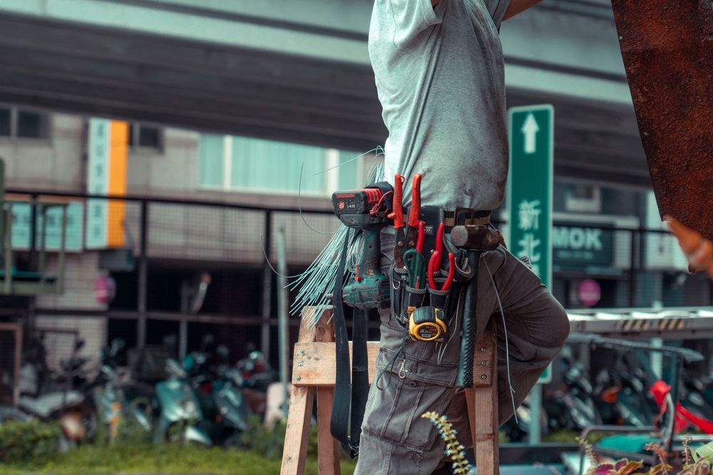 Technicien sur une échelle en intervention extérieure avec ceinture à outils