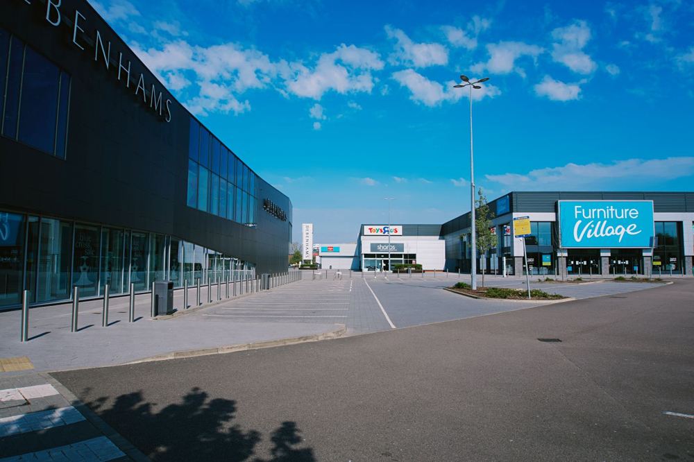 Façade d’un centre commercial avec grandes enseignes et parking