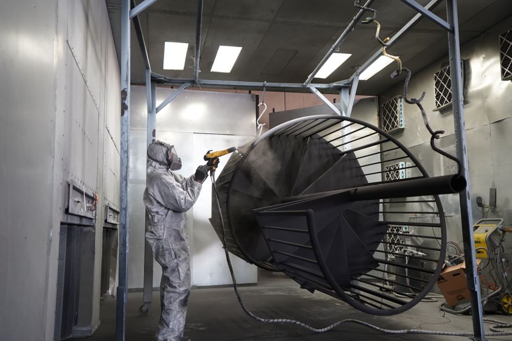 Technicien réalisant le thermolaquage d’une structure métallique en atelier
