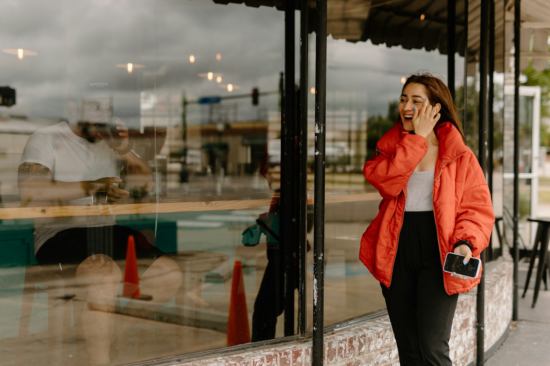 passante qui consulte son téléphone devant la vitrine d'un commerce