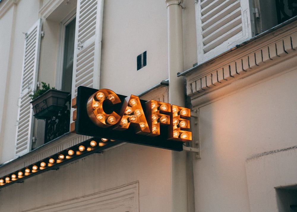 Enseigne circulaire lumineuse de café sur une façade de style parisien