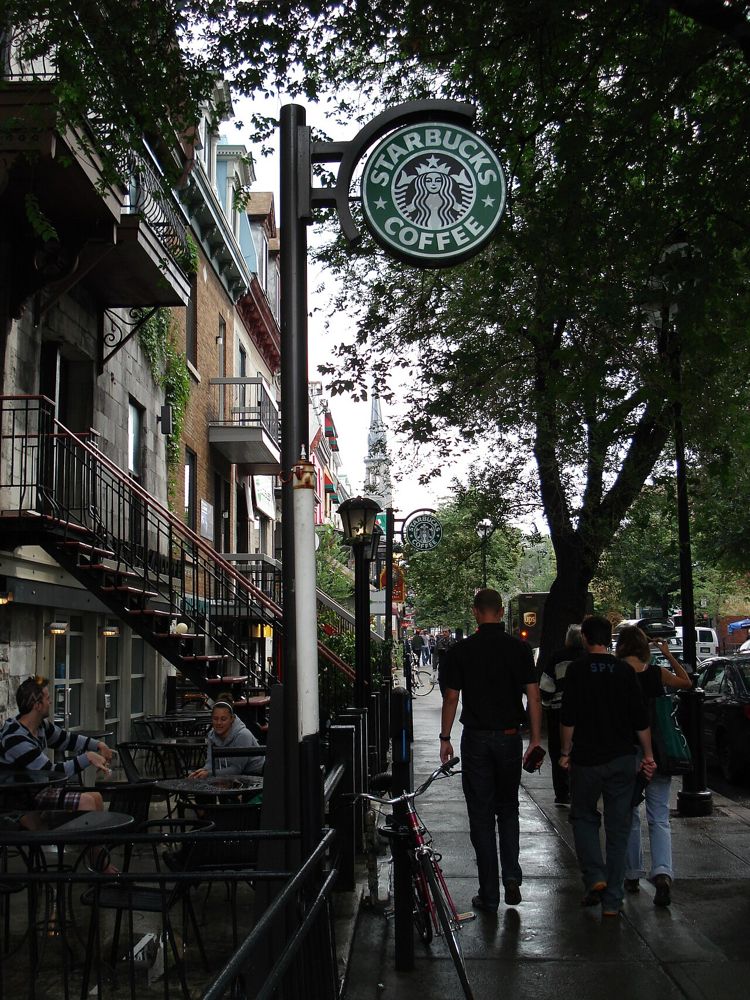 Enseigne circulaire Starbucks Coffee installée sur une façade de boutique