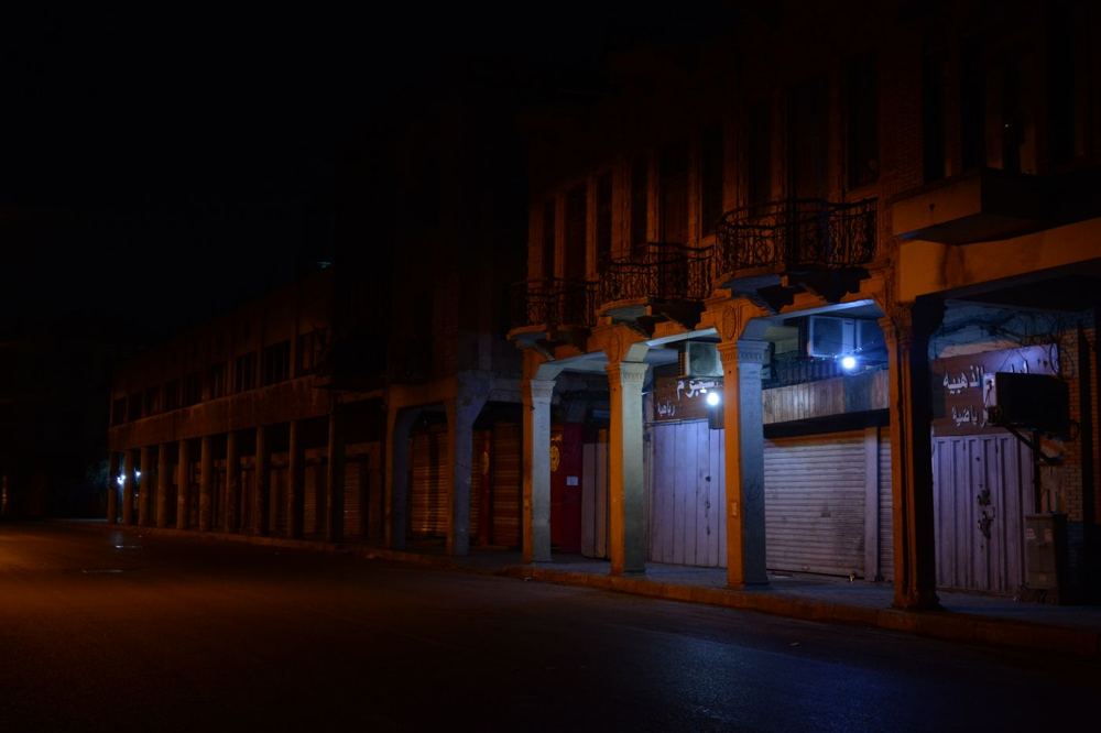 Rue commerçante calme avec enseignes éclairées puis éteintes la nuit