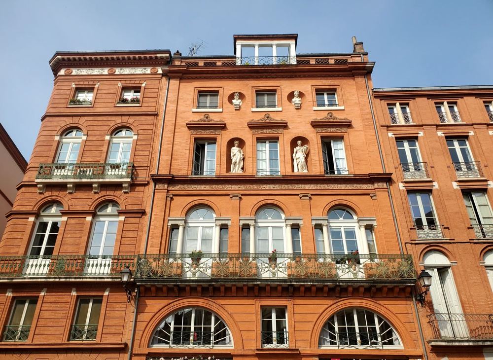 Façade en brique rouge de style toulousain, place de la Trinité