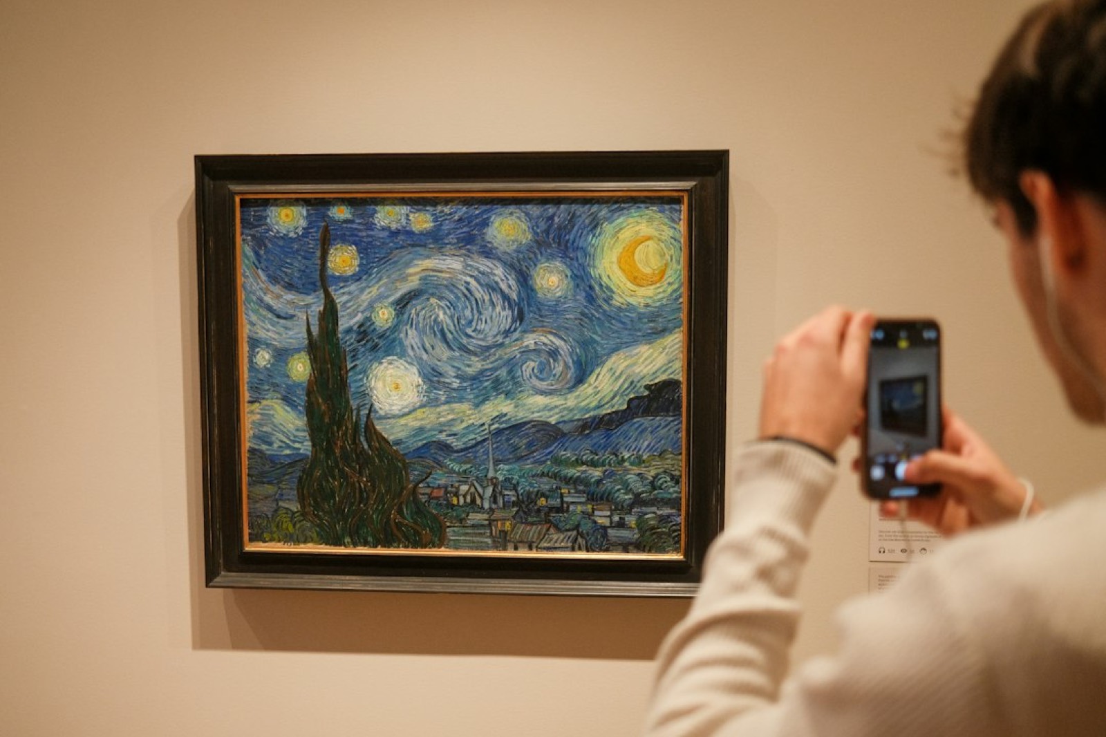 Smartphone tenu devant un tableau pour le photographier avant une estimation en ligne