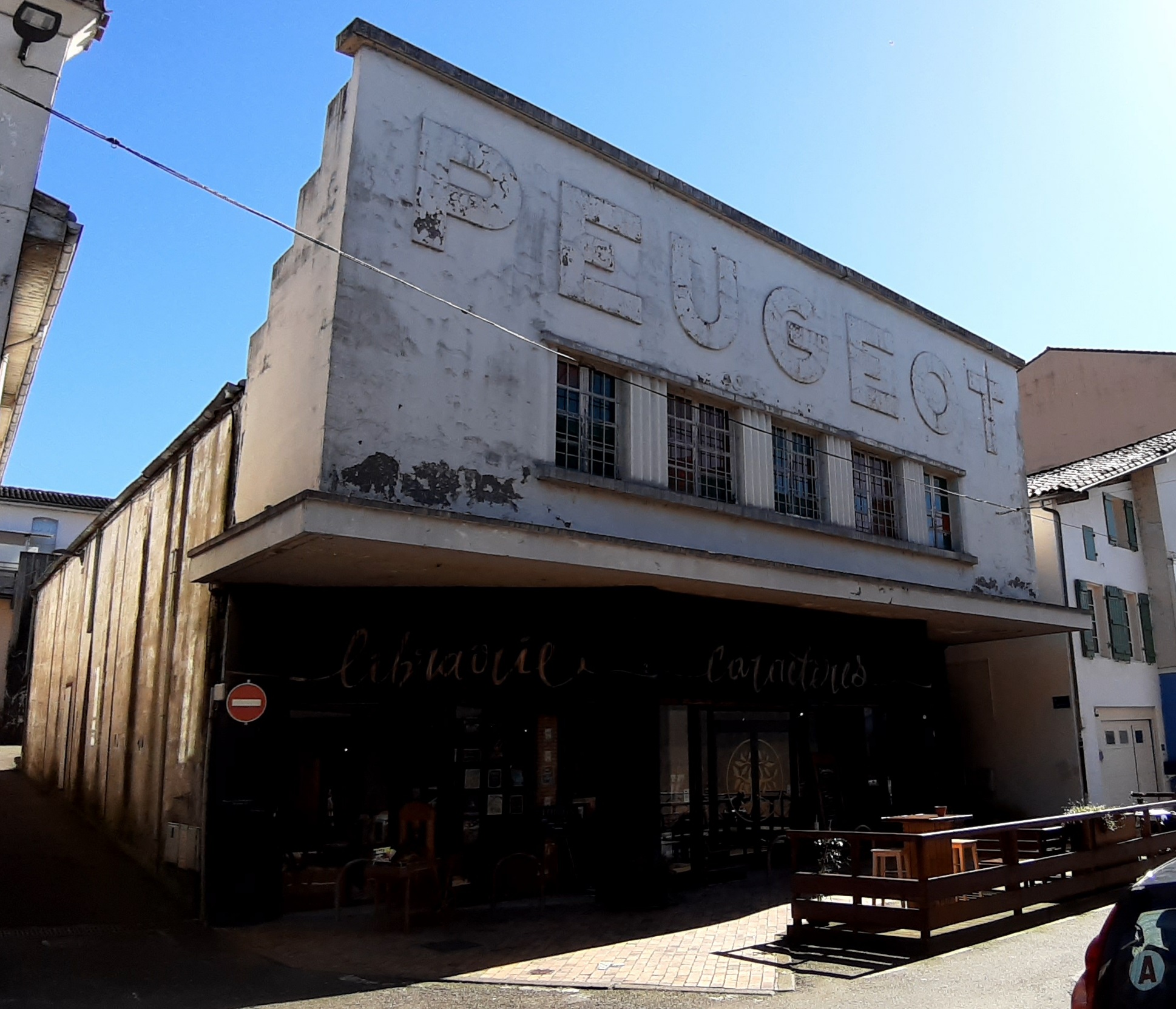 Façade d'un garage Peugeot avec enseigne murale de la marque